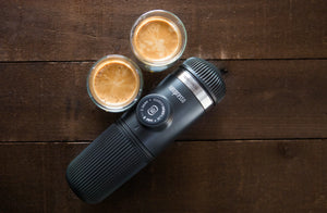 Portabel Espressomaschinn mat zwee Tassen Espresso op enger Holzuewerfläch, vu portablen Kaffisapparaten a Barista-Ausrüstung